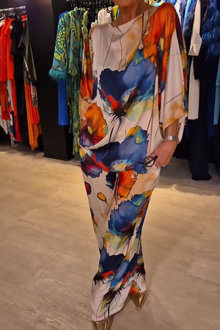 Woman wearing a long dress with abstract watercolor floral print in blue, orange, yellow, and red on cream background