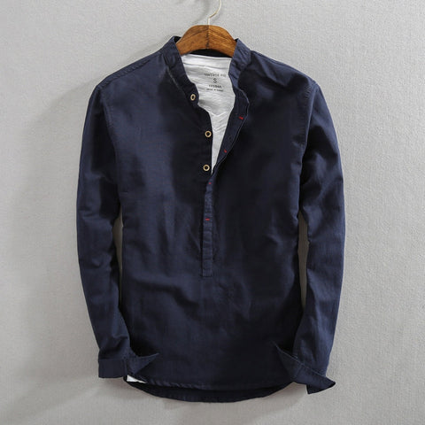 Dark navy cotton pullover shirt on wooden hanger with white undershirt visible, button placket at collar, long sleeves