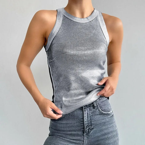 Person wearing gray ribbed sleeveless tank top with white trim, paired with dark denim jeans, standing against white