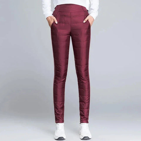 Person wearing burgundy quilted pants with side pockets and white sneakers, paired with white long-sleeved shirt, standing