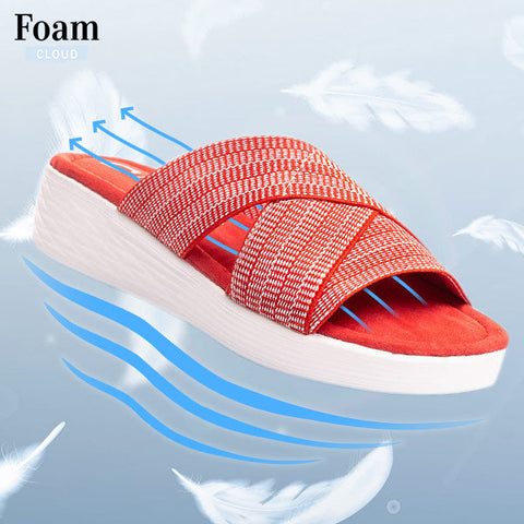 Red and white foam slide sandal with textured straps, shown on layered white and blue sole against cloudy blue background.