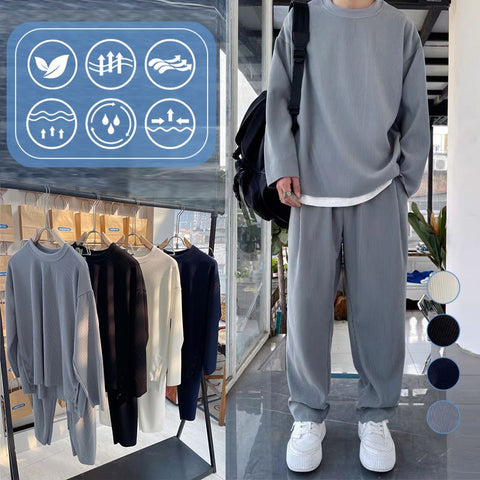 Person wearing gray crewneck sweatshirt and matching gray sweatpants with white sneakers, standing in retail display