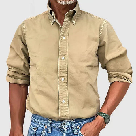 Tan button-up shirt with rolled sleeves on man wearing blue jeans, white stitching visible on collar and front placket.