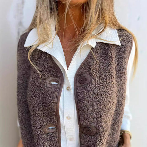 Woman wearing brown textured wool vest over white collared shirt, blonde hair visible, neutral background.