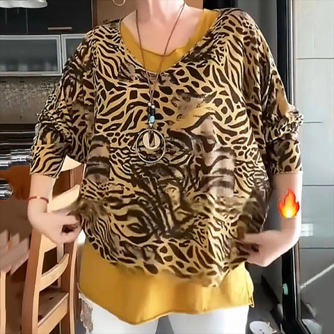 Person wearing brown and tan animal print tunic with three-quarter sleeves over yellow top, standing in kitchen with pendant