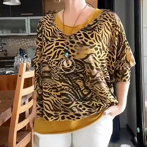 Woman wearing short-sleeved animal print top with brown and tan zebra and leopard pattern, mustard yellow trim and