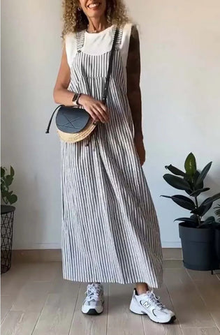 Woman wearing white sleeveless t-shirt layered under gray and white striped sleeveless dress, paired with white sneakers and