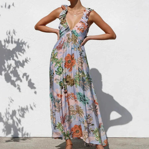 Woman wearing sleeveless floral maxi dress with deep V-neckline and ruched shoulders. Dress features multicolored flowers on